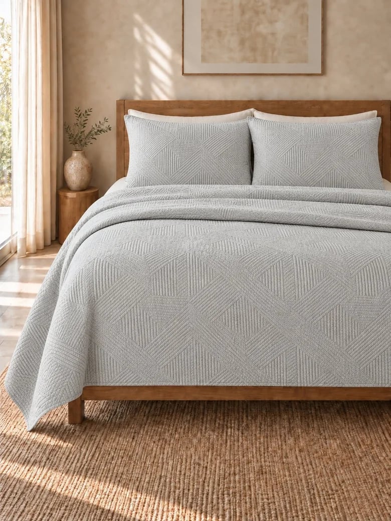 Grey and ecru cotton matelassé coverlet with matching shams on a wooden bed